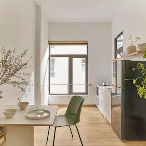 Een moderne keuken met een eethoek, een groot raam en een zwarte koelkast.