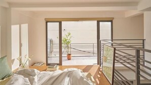 Una stanza con un letto, una finestra, una pianta e vista sull'esterno.