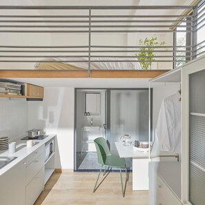 Une cuisine moderne avec un coin repas, une plante visible et un escalier menant à un niveau supérieur.