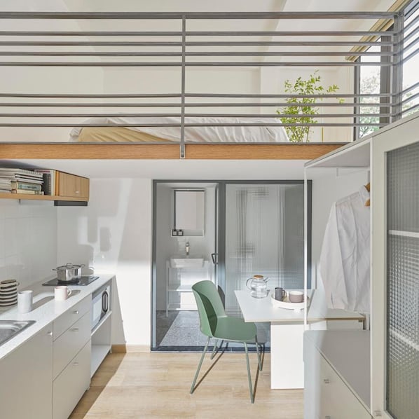 Een moderne keuken met een eethoek, een zichtbare plant en een trap naar een hoger gelegen verdieping.
