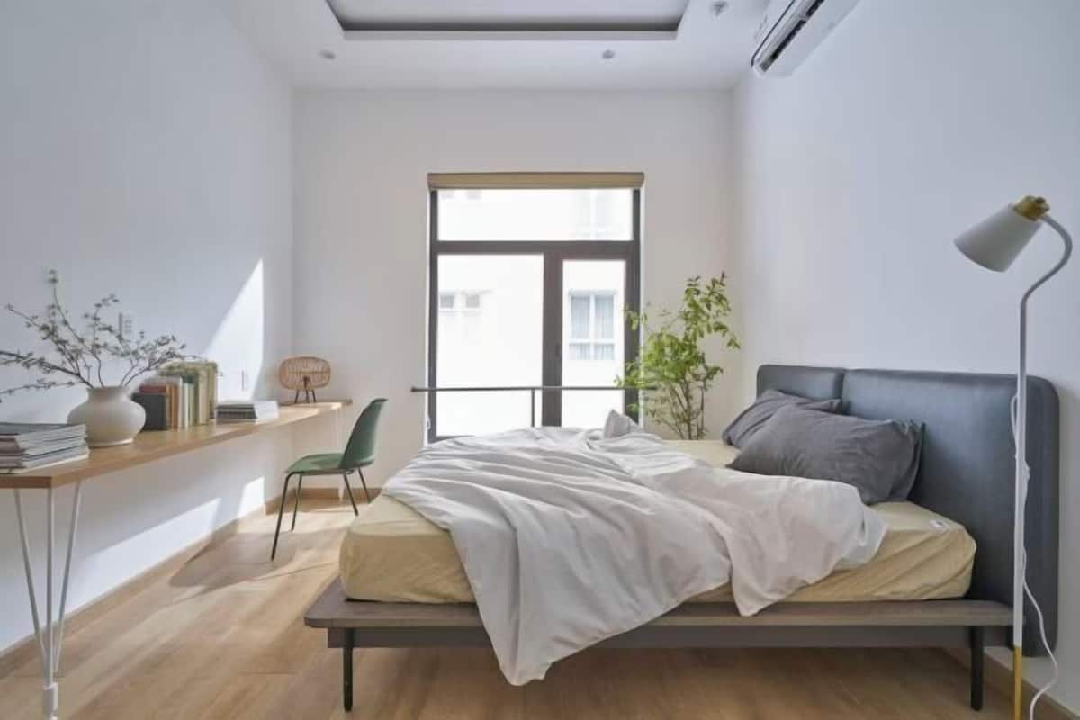 Une chambre à coucher au style minimaliste, avec un lit, un bureau, une chaise et une fenêtre.