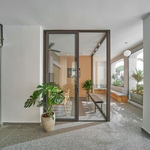 Een modern interieur met een schuifglazen deur naar een zithoek met een bank en planten.