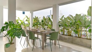 Ein moderner Essbereich mit Tisch und Stühlen, umgeben von großen Kübelpflanzen und Blick auf die Stadt.