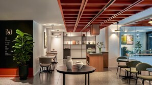 A modern interior with a reception desk, seating area, and a view of the outdoors. - Express by M Village Nguyen Du, a brand of Modern Village Lifestyle (Ho Chi Minh City)
