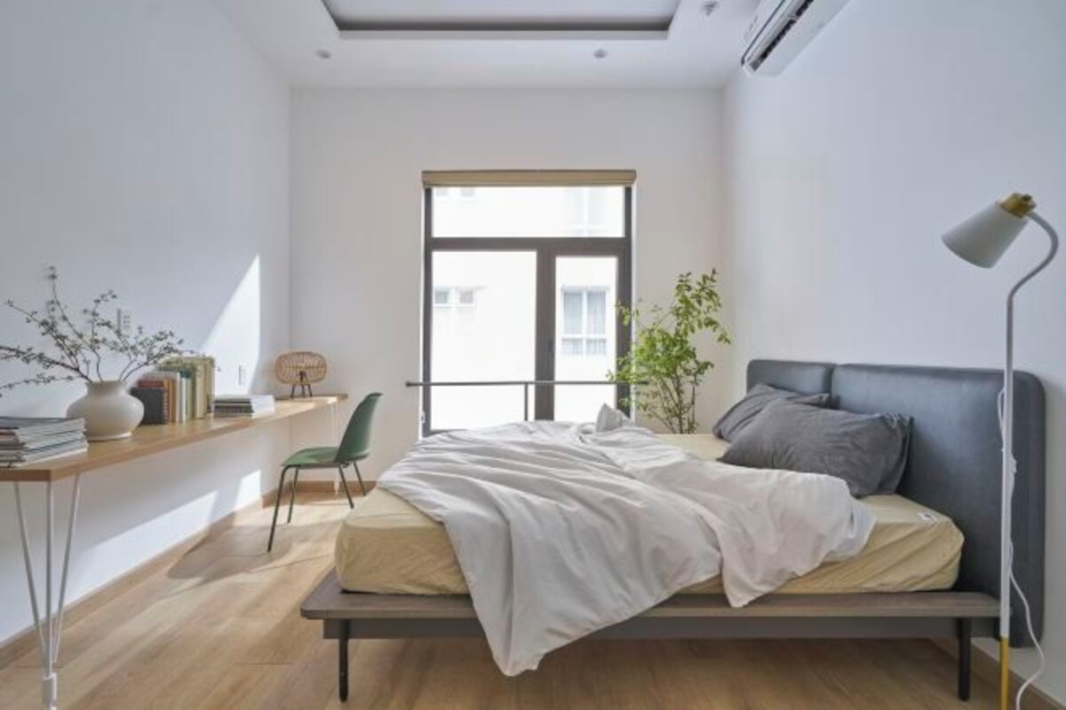 Une chambre à coucher au style minimaliste, avec un lit, un bureau, une chaise et une fenêtre.