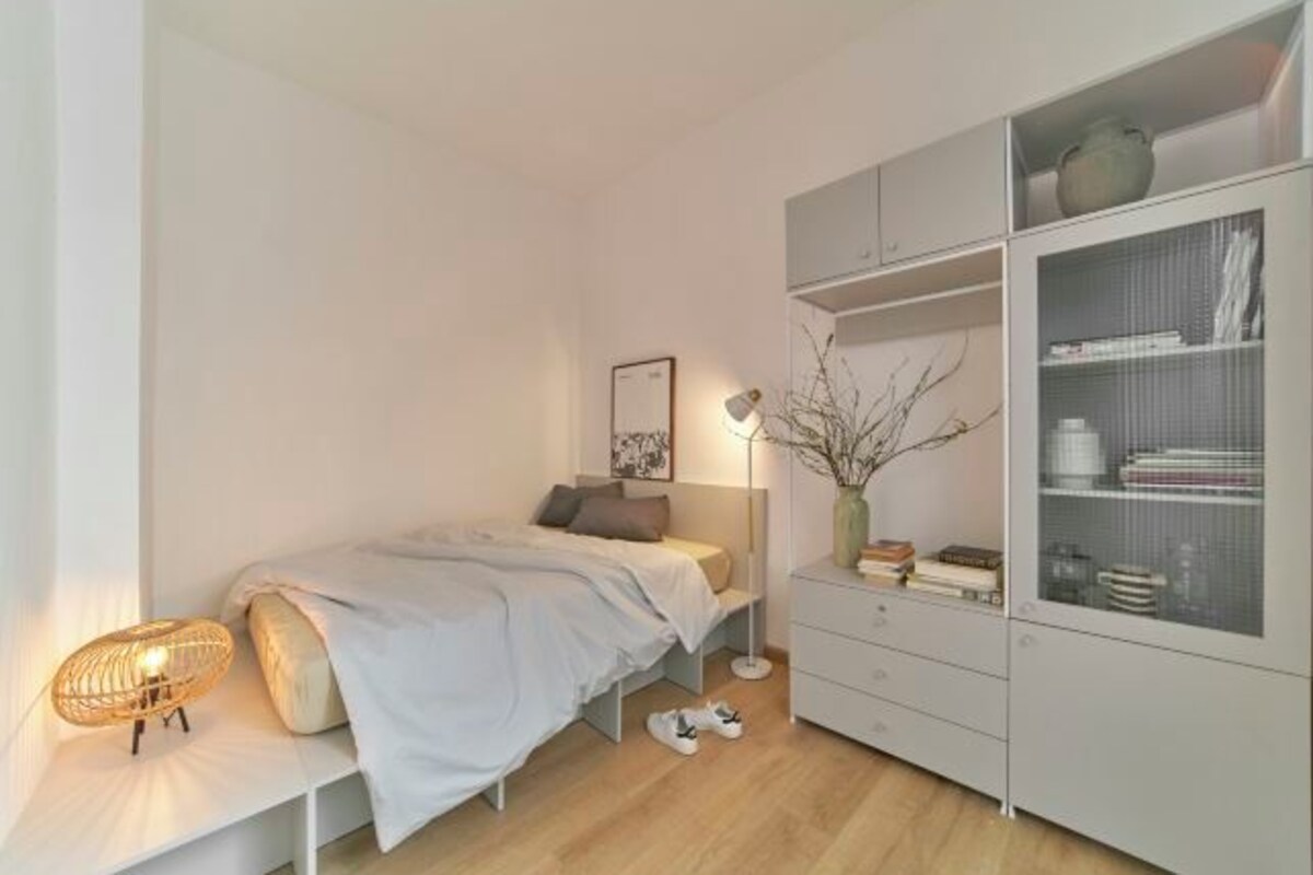 Une chambre à coucher avec un lit, une lampe de chevet et une armoire.
