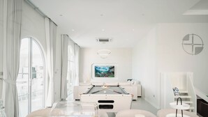 Una habitación moderna y bien iluminada con mesa de billar, asientos cómodos y un amplio ventanal con vistas al exterior.