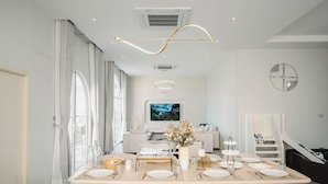 Un comedor moderno con una mesa larga dispuesta para seis personas, un sofá al fondo y una escalera que sube a un nivel superior.