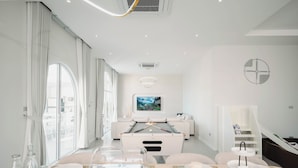 Una habitación moderna y bien iluminada con una mesa de billar, un sofá y un comedor con una mesa preparada para dos personas.