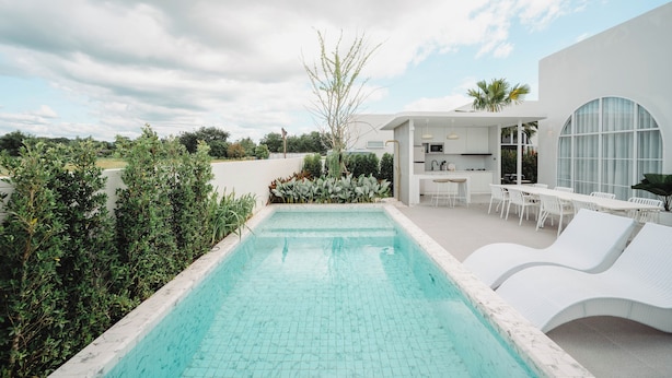 Un área de piscina exterior moderna con un conjunto de comedor y sillones de descanso.