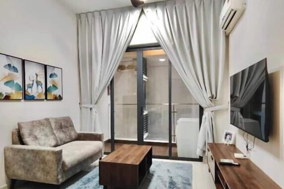 A living room with a sofa, coffee table, TV, and a ceiling fan.