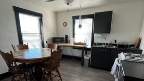 A compact kitchen with a dining area, a ceiling fan, a microwave, a sink, and a stove.