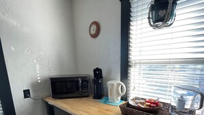 A kitchen with a microwave, coffee maker, and a hanging plant.