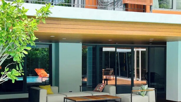 A modern outdoor living area with a pool, featuring a sofa set, a coffee table, and a dining table. - Tierra Residence (Bangkok)