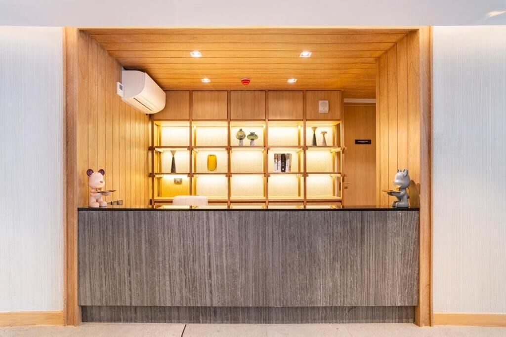 A reception area with a wooden ceiling, a grey reception desk, and shelves with various items.
