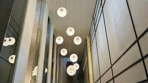 A corridor with modern pendant lighting and a geometric wall design. - Tierra Residence (Bangkok)