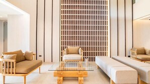 A modern living room with a sofa, a chair, and a glass coffee table. - Tierra Residence (Bangkok)