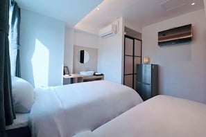 Habitación de hotel con dos camas, una mesita de noche, un espejo, un lavabo y un televisor.