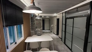 Un espacio de oficina moderno con una larga mesa y sillas, una pared de ladrillo decorativa y un pasillo que lleva a una puerta.
