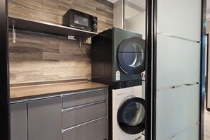 A compact laundry area with a washing machine, a dryer, and a microwave on a wooden shelf. - D STAY HOSTEL dongdaemun (Seoul)