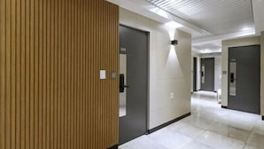 Un pasillo moderno con un revestimiento de paneles de madera, una puerta identificada con 'S04' y un piso de baldosas.