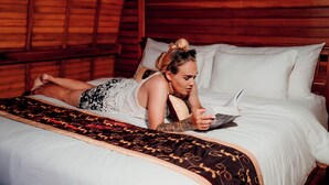 A wooden cabin interior with a bed, a blanket, and a person lying on the bed. - Nusa Dua Huts Pondok Gajah Para by EPS (Nusa Dua)