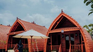 A wooden villa with a swimming pool, lounge chairs, and a covered patio area. - Nusa Dua Huts Pondok Gajah Para by EPS (Nusa Dua)