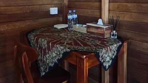 A wooden interior with a table set for two, featuring a patterned tablecloth and a bottle of water. - Nusa Dua Huts Pondok Gajah Para by EPS (Nusa Dua)