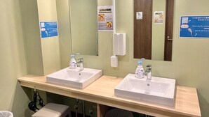 A restroom with two sinks, a mirror, and a trash bin. - Otemachi Kamon Hotel - Caters to Men - Hostel (Tokyo)