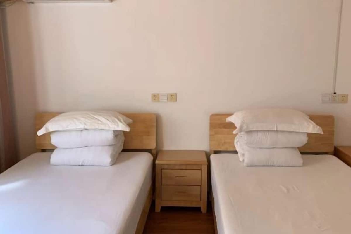 A room with two single beds, each with a wooden headboard and a small bedside table.