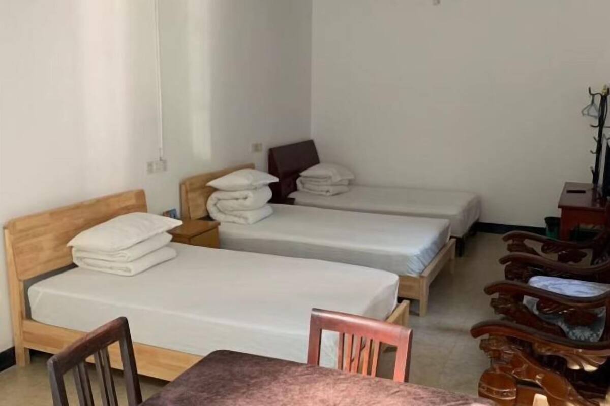 A room with two single beds, a wooden chair, and a small table.