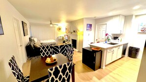 A modern kitchen with a central island, a dining area with patterned chairs, and a living room with a sofa and a TV. - Cozy Marina del Rey Stay Near the Beach (Marina del Rey)