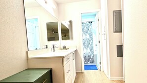 A narrow hallway leading to a bathroom with a large mirror, a vanity with drawers, and a door with a patterned curtain. - Cozy Marina del Rey Stay Near the Beach (Marina del Rey)
