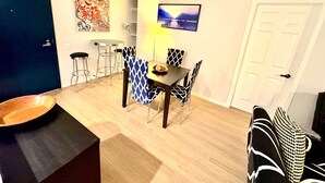 A dining area with a table and chairs, a bar stool, a wooden bowl, and a painting on the wall. - Cozy Marina del Rey Stay Near the Beach (Marina del Rey)