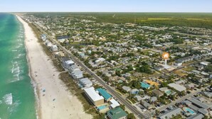 Luftaufnahme einer Küstenstadt mit Strand, Wohngebieten und einem markierten Ort.