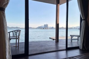Ein Zimmer mit Blick auf ein Gewässer, eine Holzterrasse und zwei Stühle.