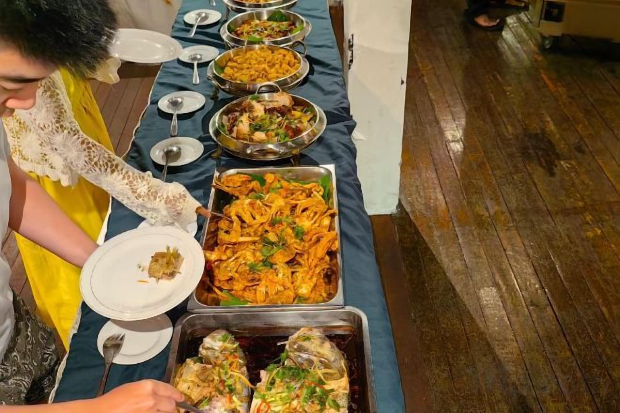 Una mesa de buffet con diversos platos y una persona sirviendo comida.