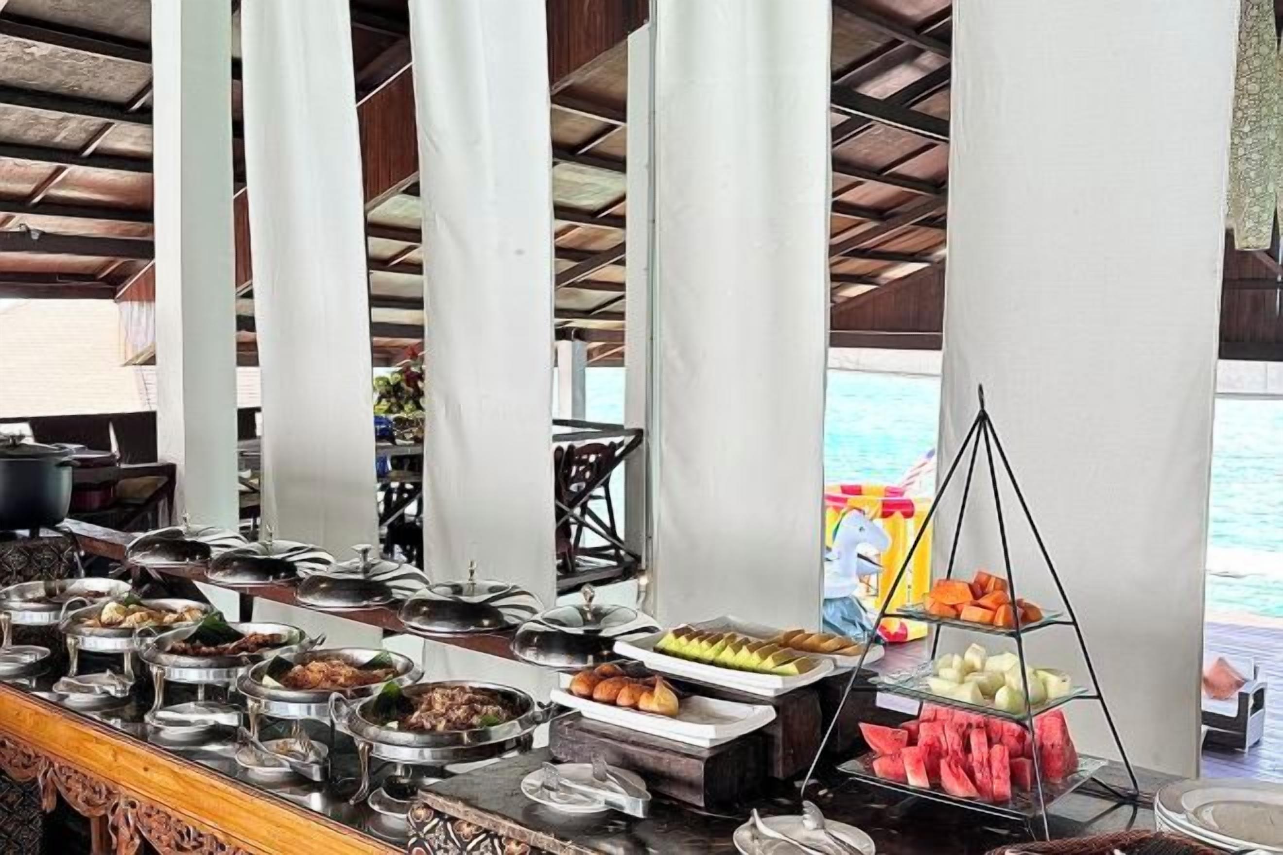 A buffet setup with various food items and a view of the sea.
