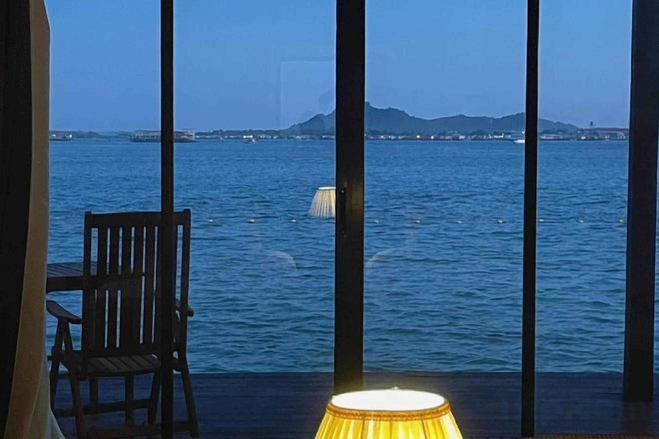 Una stanza con vista sul mare, una sedia e una lampada.