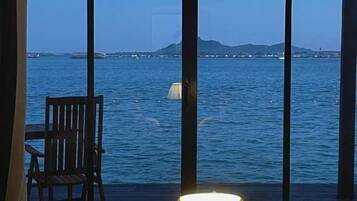 Una stanza con vista sul mare, una sedia e una lampada.