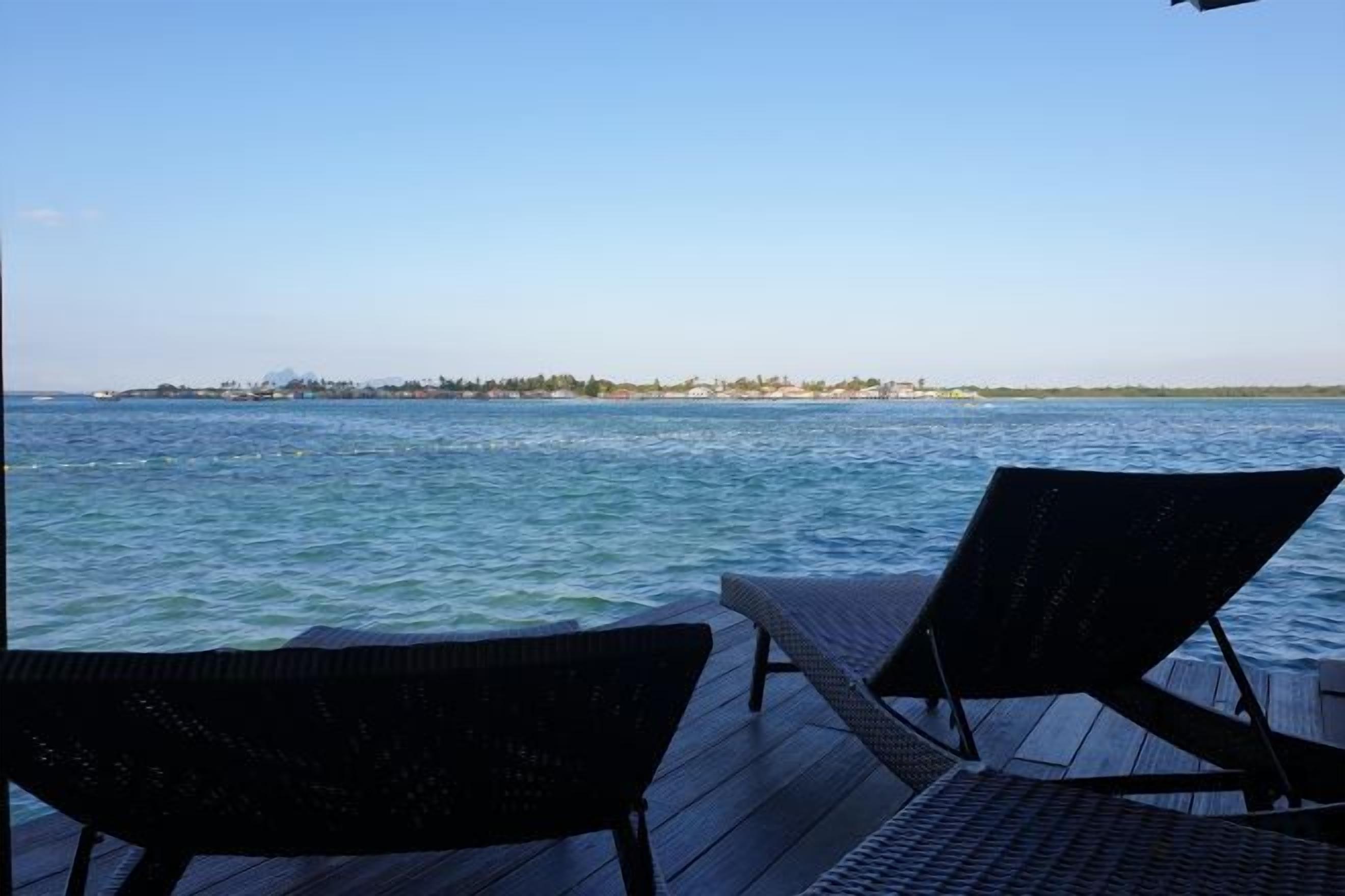 Una terraza con dos sillones de descanso con vista a una masa de agua y una costa distante.