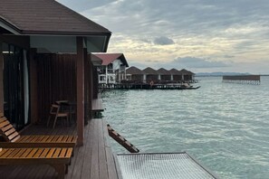 A wooden deck with lounge chairs, a covered seating area, and overwater bungalows in the background. - Sea Star Resort Semporna (Semporna)
