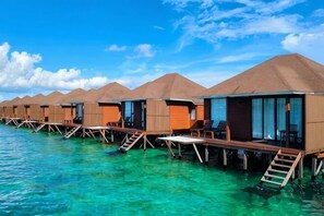 Bungalows sobre el agua con estructuras de madera, agua azul cristalina y un cielo despejado.