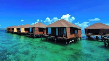 Bungalow sull'acqua con strutture in legno e pareti aperte, galleggianti su acque cristalline turchesi.