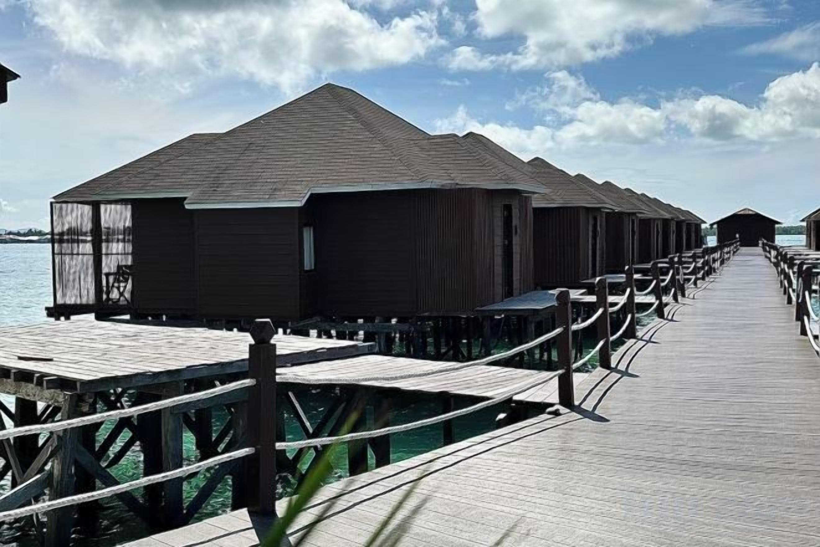 Lyxiga bungalows byggda på pålar över vattnet, sammanlänkade med en träpromenad som går över vattnet.