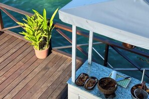 A wooden deck with a potted plant, a table with a white tablecloth, and a metal bowl. - Sea Star Resort Semporna (Semporna)