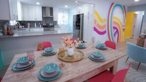 Una cucina moderna con mobili bianchi, un'isola centrale e un vivace murale.