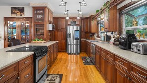 Una cocina con armarios de madera, electrodomésticos de acero inoxidable e iluminación colgante.