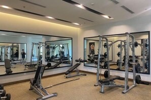 Une salle de sport avec des murs recouverts de miroirs, des appareils de musculation et un sol moquetté.