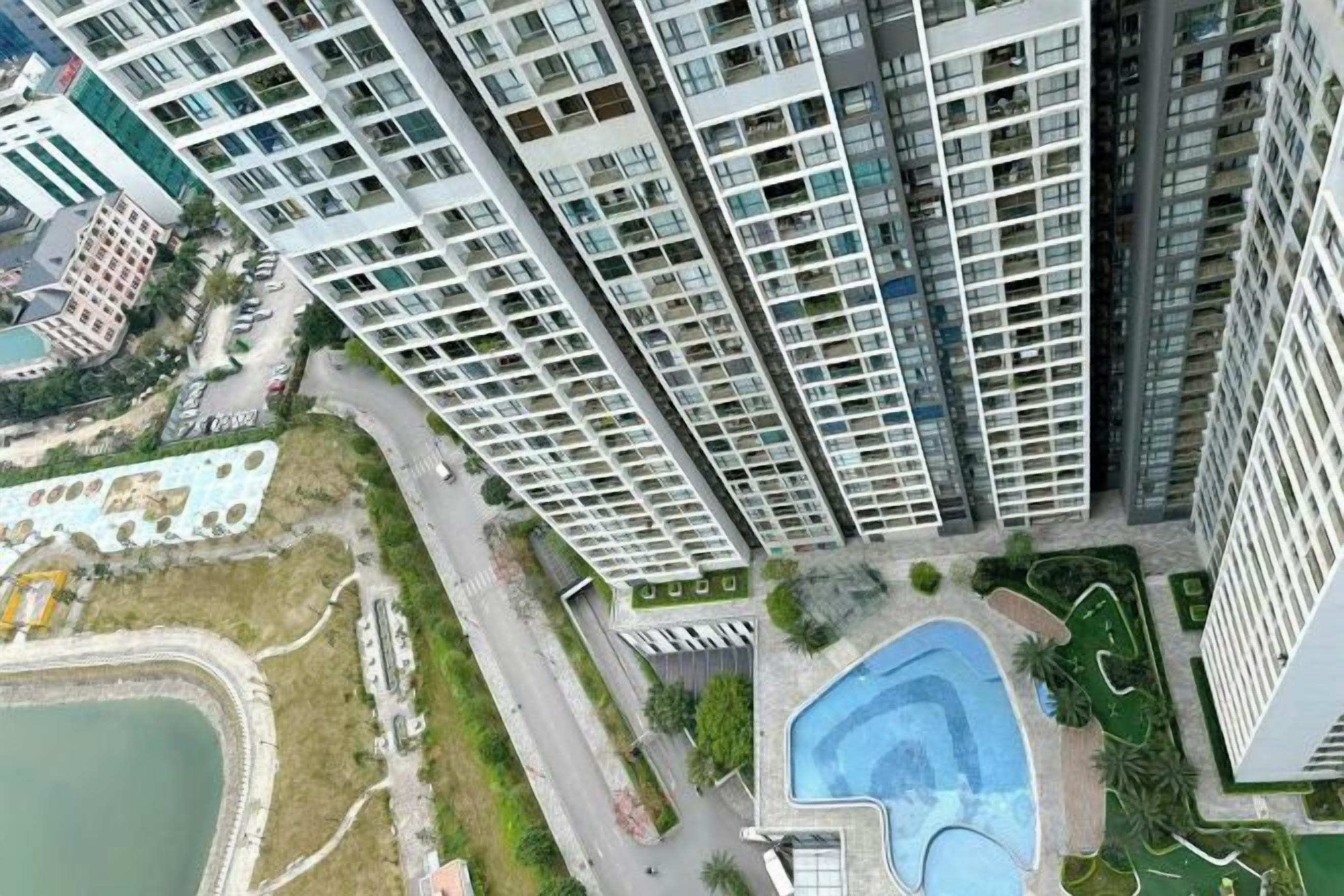 Un immeuble résidentiel de grande hauteur doté de nombreux balcons, d’une piscine et d’un espace paysager.